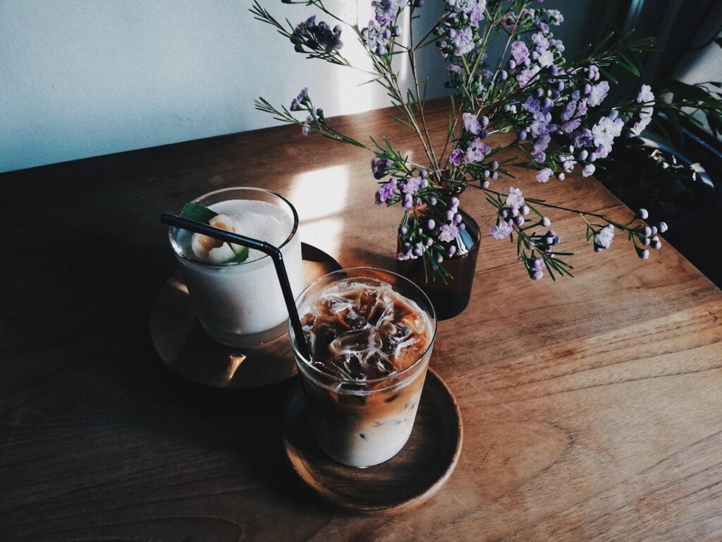 Two iced beverages with florals on a wooden table create a refreshing indoor setting.